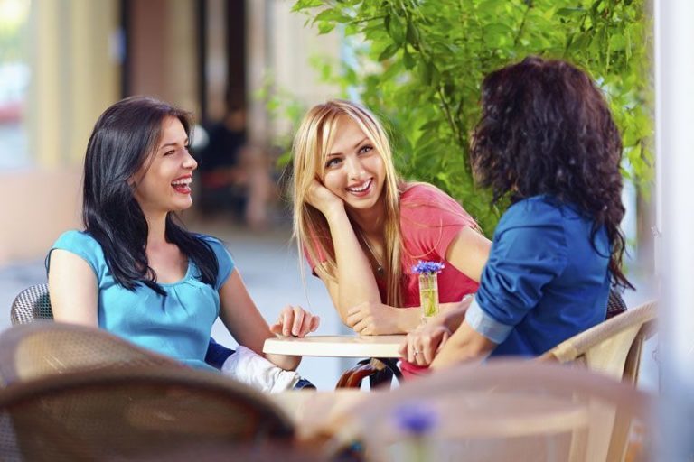 group of three women chatting and sitting around a table