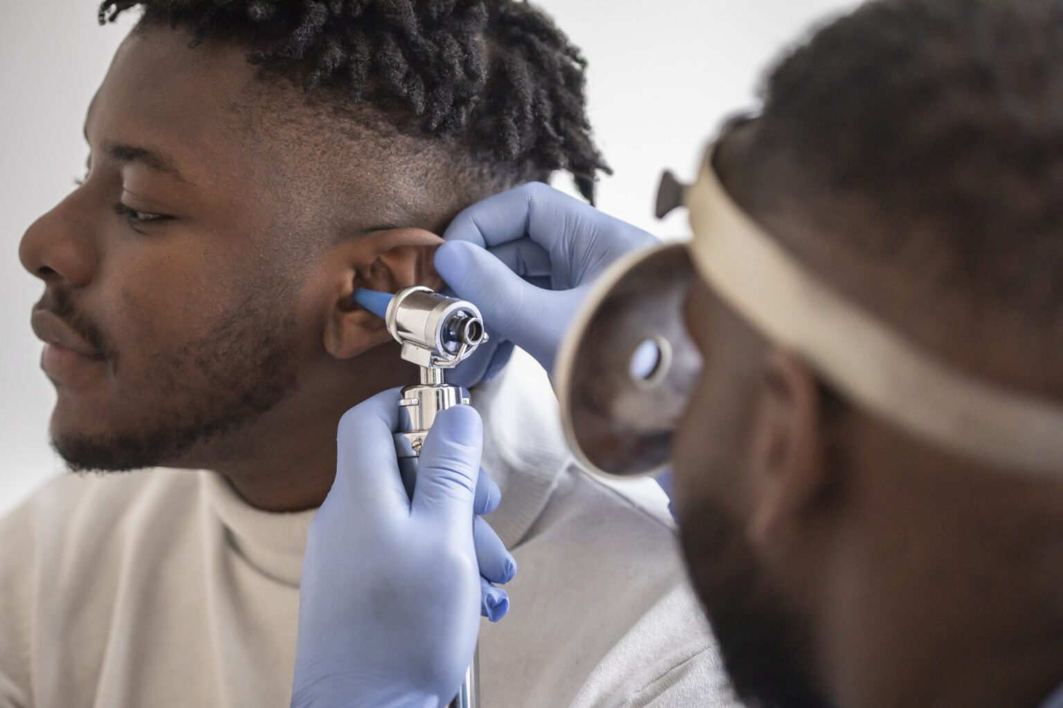 Close up of a male doctor carefully holding the ear of his patient to establish a clearer view of the inside of his ear, to see if he requires hearing aids at a modern clinic