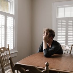 Depressed man sitting with head in hands at his table.
