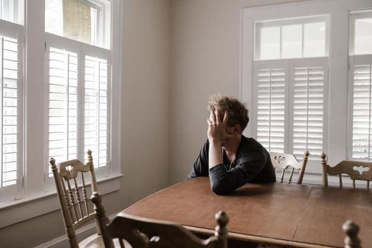 man-depressed Depressed man sitting with head in hands at his table.