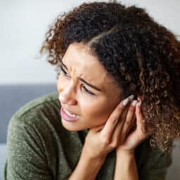 Woman with an ear infection pressing her ear.