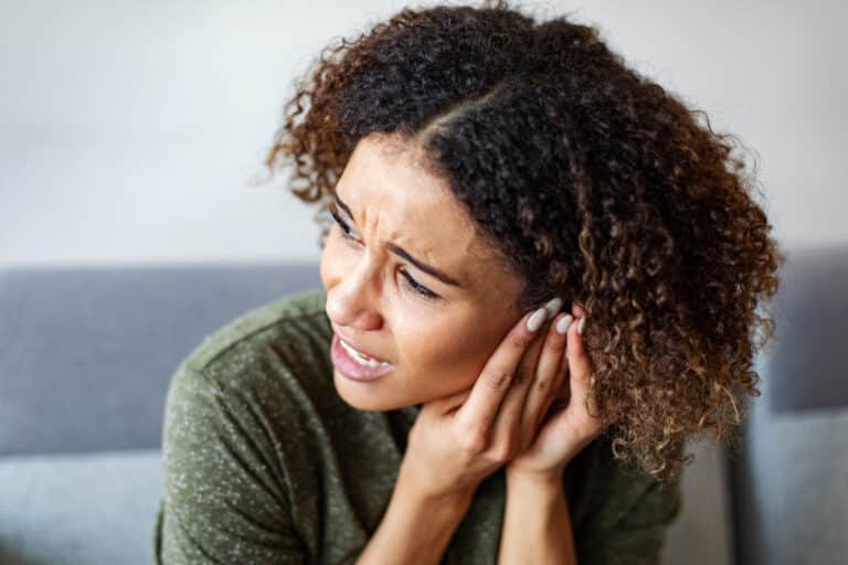 woman-pressing-ear-ear-infection-hearing-loss Woman with an ear infection pressing her ear.