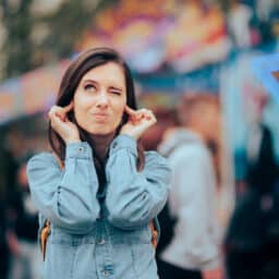 Woman covering her ears around loud noise