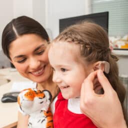 Young girl looking happy getting her first hearing aid