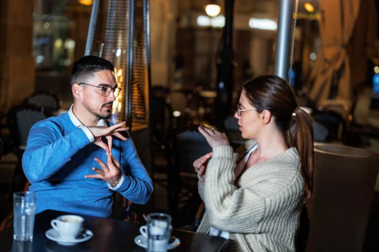 Couple signs to one another at restaurant