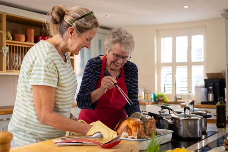 Cooking The Thanksgiving Turkey Senior woman and her daughter basting a turkey