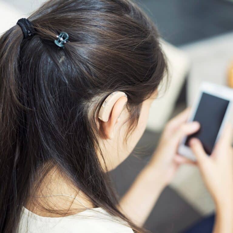Woman with hearing aids using her hearing aid bluetooth app Woman with hearing aids using her hearing aid bluetooth app